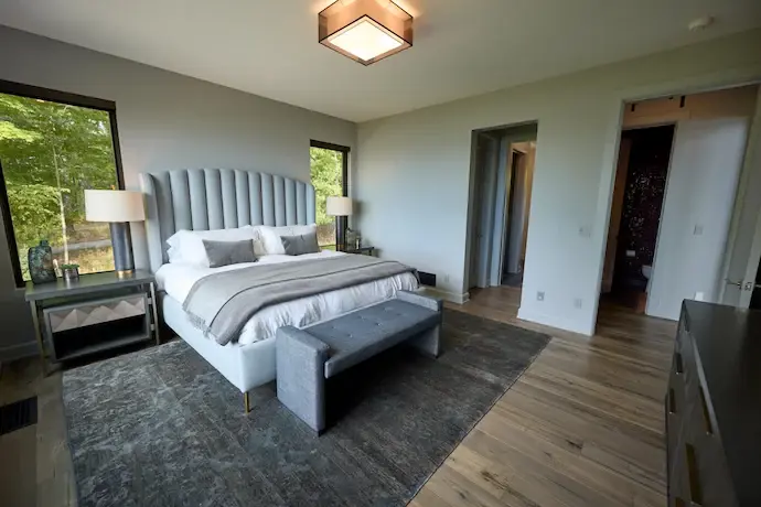 a bed with white sheets, nightstand, dresser with sign above it, carpet flooring