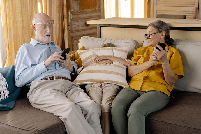 two seniors sitting on the couch using their phones in a renovated senior living center