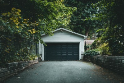 freshly painted garage surrounded by lots of green trees 