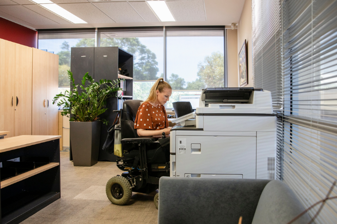 a woman in the wheelchair using a printer