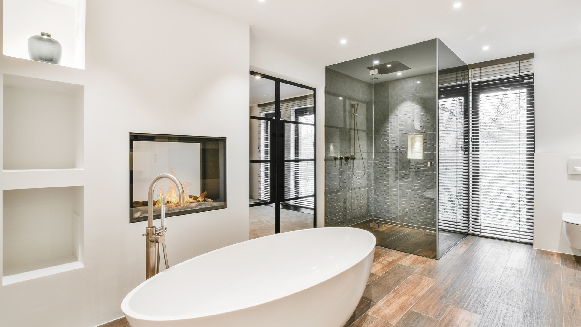 White bathroom with wood flooring featuring a large tub and walk-in shower