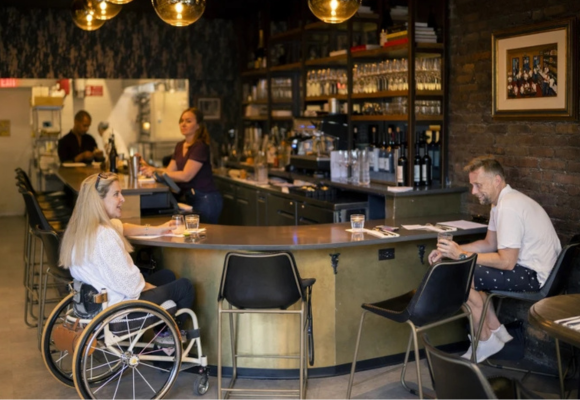 a woman in the wheelchair sitting at the bar with a guy