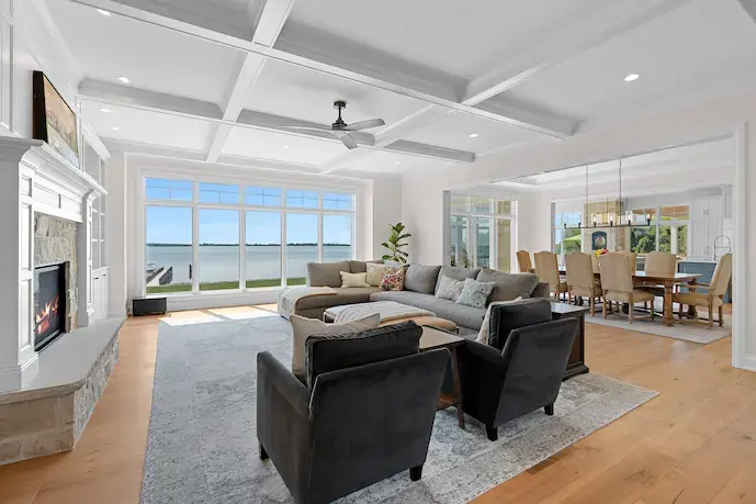 grey sectional with the abstract picture behind, coffee table in the middle, hardwood flooring with the rug in the couch area