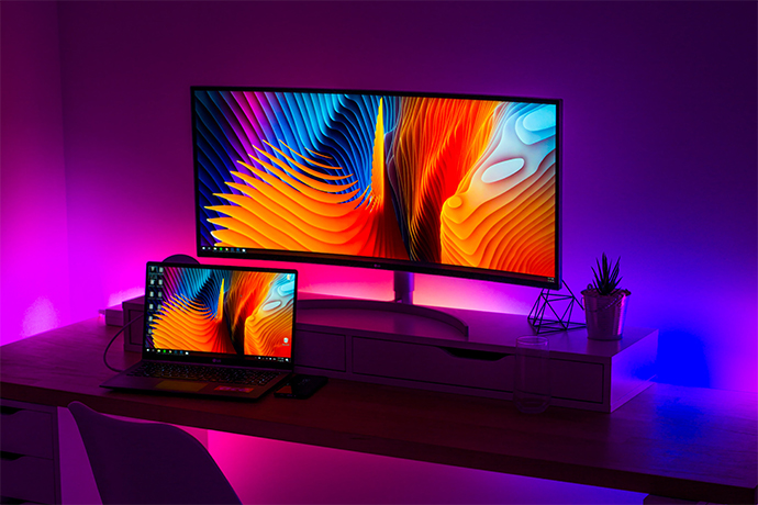 Purple, blue and magenta led lights setup behind computer workstation.