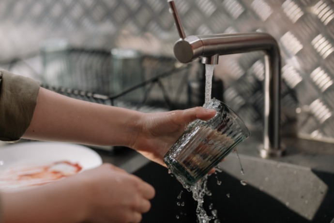 a person washing the glass in the kitchen sink