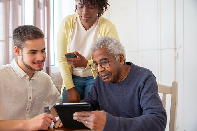 Staff at senior living center helping an older man to use the tablet