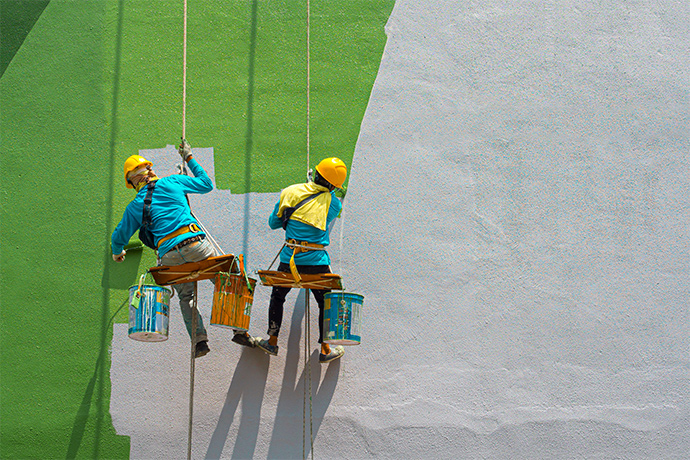 two men painting the wall from grey to green