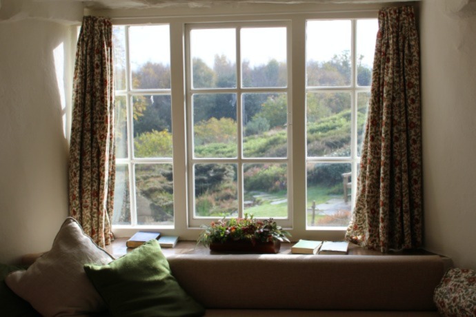 big window with green field and trees outside and a couch in front 