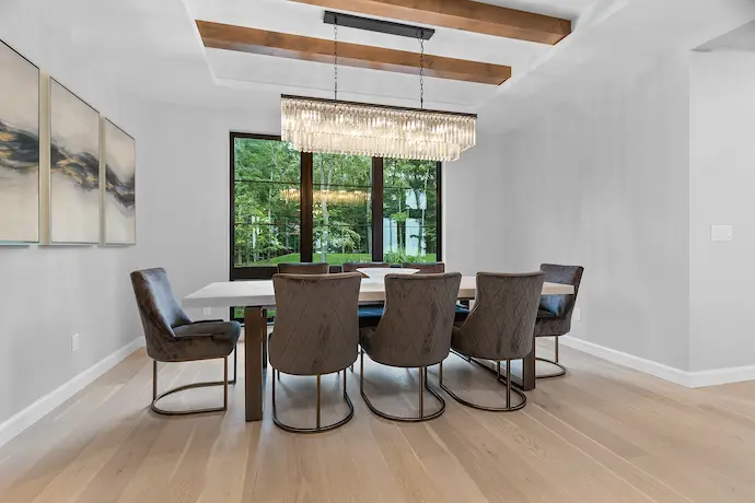 big dinning room with shiny chandelier, staircase in the back 