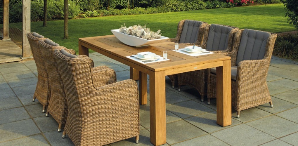 a patio with a big wooden table and six patio chares with a lawn in the back