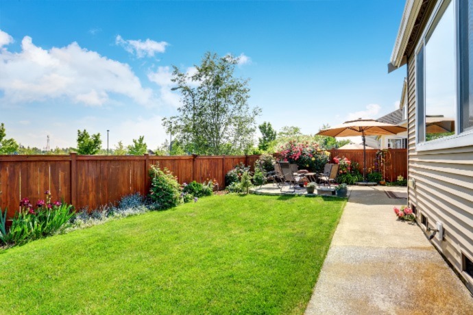 back yard with bright green lawn and a wooden fence