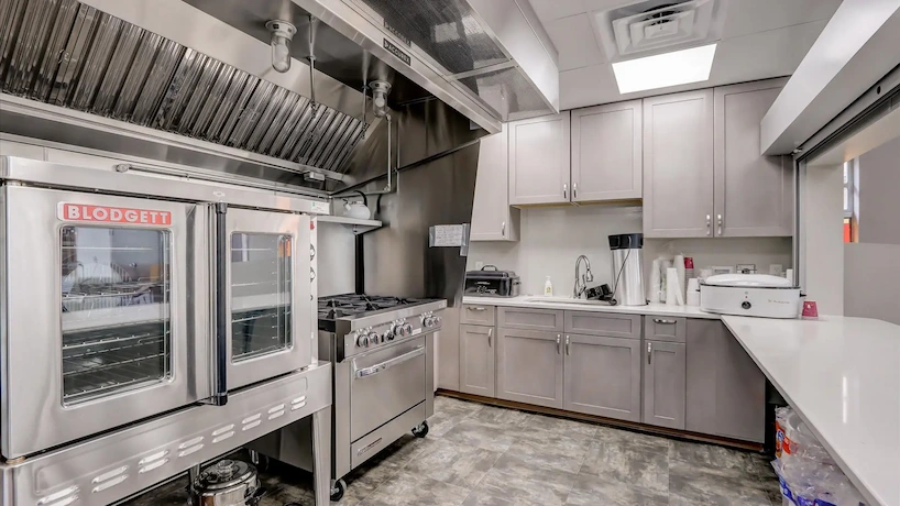 Newly renovated commercial kitchen space with fresh cabinetry and commercial ovens