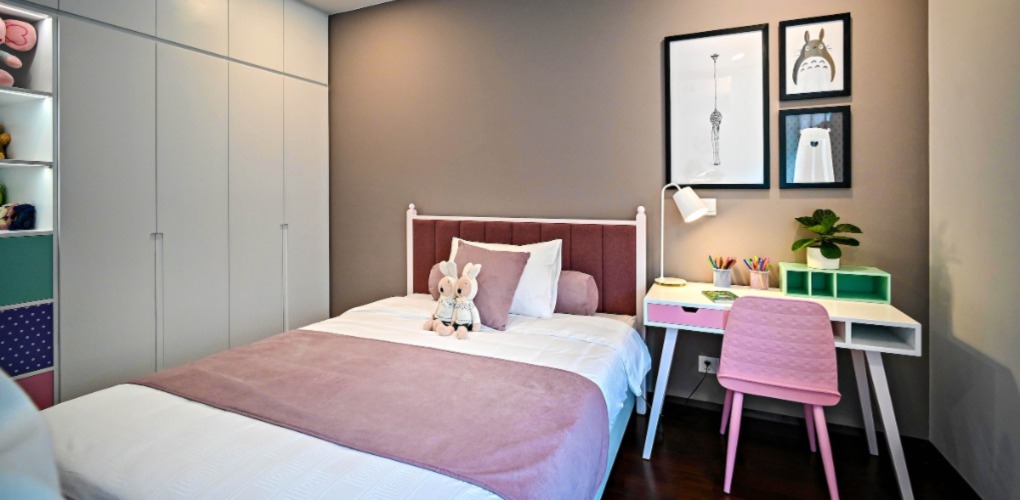 simple kids' bedroom with the bed, a desk on the right and some pictures on the wall