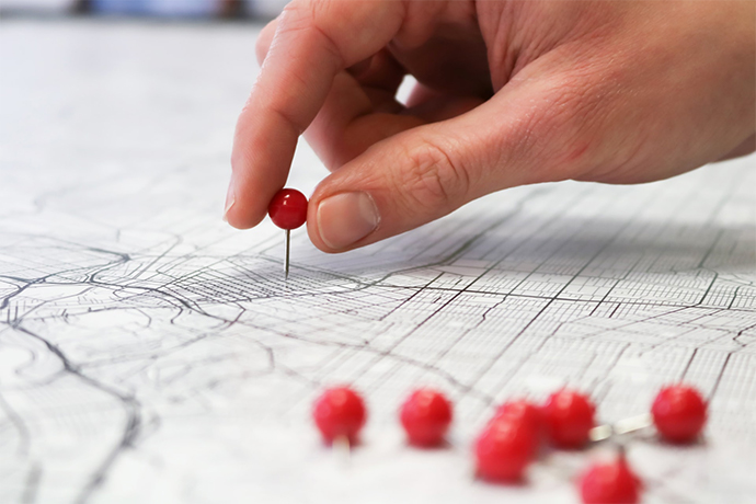 a hand putting red pin on the paper with construction plan