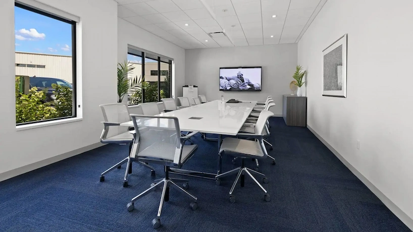 newly renovated office conference room with blue carpet and white conference table