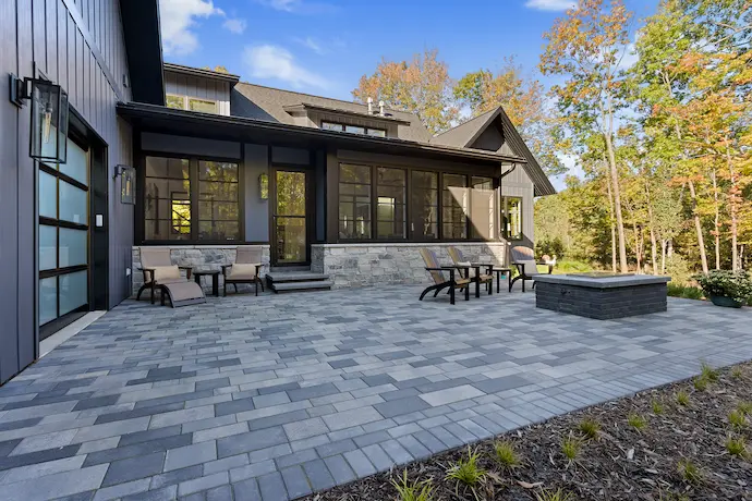 a patio with a big wooden table and six patio chares with a lawn in the back