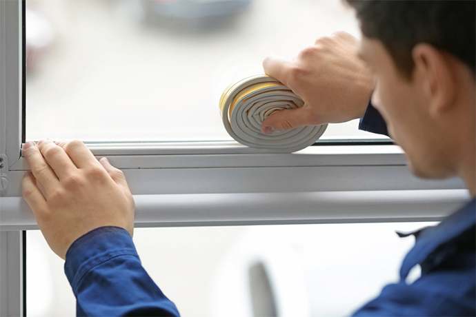 a man sealing the window with sealing tape to prepare it for the winter